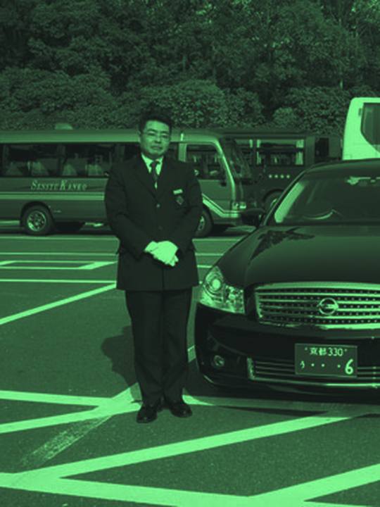 Chauffeur standing beside a black sedan