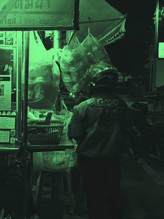 Food delivery rider waiting at a night food stall